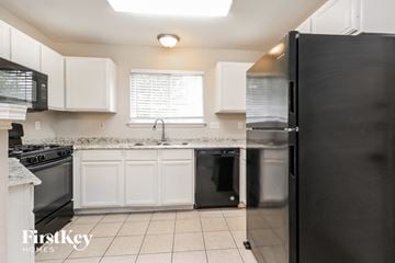 Houston house for rent - A kitchen with white cabinets and black appliances.