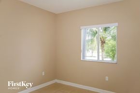 Miami house for rent - A room with a window showing a view of trees and a palm tree.