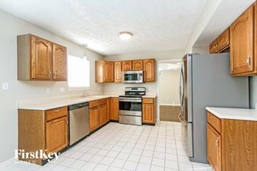 Brownsburg house for rent - A kitchen with wooden cabinets and a white tile floor.