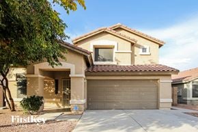Surprise house for rent - a beige house with a garage door and a tree