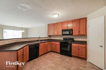 Cypress house for rent - a kitchen with wooden cabinets and black appliances