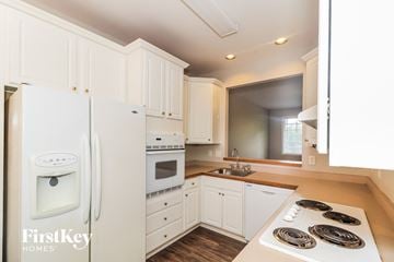Cumming house for rent - a kitchen with white cabinets and a white stove and refrigerator