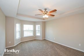 Jacksonville house for rent - an empty living room with a ceiling fan and windows
