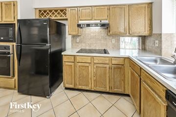 Houston house for rent - a kitchen with wooden cabinets and a black refrigerator