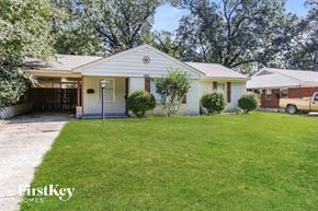 Memphis house for rent - A white house with a garage is surrounded by a green lawn.