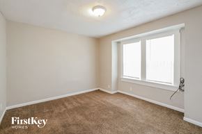 Kansas City house for rent - a bedroom with a large window and a carpeted floor