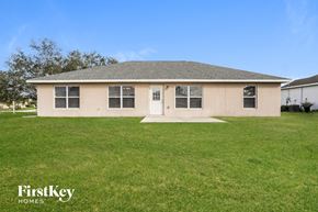 Cape Coral house for rent - a beige house with a grassy yard and a blue sky