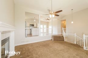 Raymore house for rent - A spacious living room with a fireplace and a staircase.