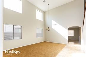 Goodyear house for rent - an empty living room with a rug and a hallway with windows
