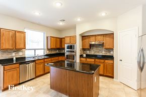 Goodyear house for rent - a kitchen with wooden cabinets and black counter tops and stainless steel appliances