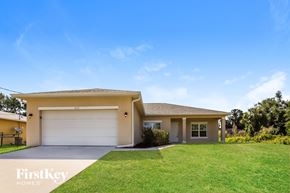 North Port house for rent - a beige house with a lawn and a garage door