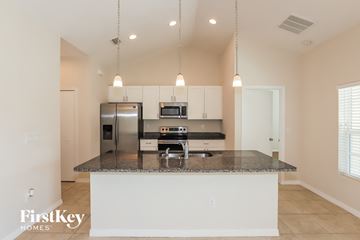 North Port house for rent - a kitchen with white cabinets and a granite counter top