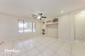 Surprise house for rent - an empty living room with a ceiling fan and a window