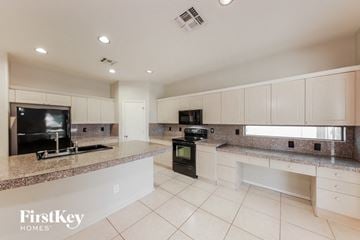 Surprise house for rent - a large kitchen with white cabinets and granite counter tops
