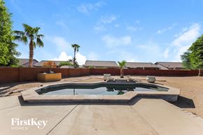 Surprise house for rent - a hot tub in the backyard of a house with palm trees