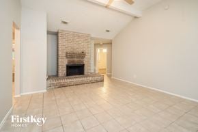 Houston house for rent - A spacious living room with a brick fireplace and tiled flooring.