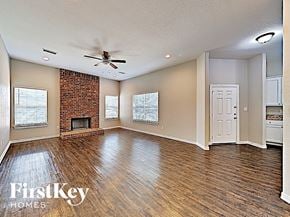 Desoto house for rent - A spacious room with a brick fireplace and wooden floors.