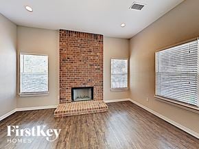 Desoto house for rent - A room with a brick fireplace and wooden floors.