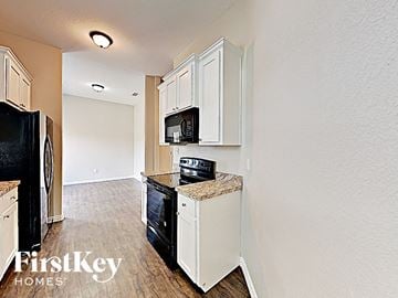 Desoto house for rent - A kitchen with white cabinets and a black fridge.