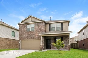 Houston house for rent - A brick house with a garage door and a tree in front.