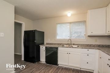 Houston house for rent - a kitchen with white cabinets and a black refrigerator