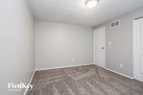 Indianapolis house for rent - the spacious living room with carpeting and a door to the bedroom