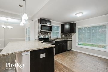 Decatur house for rent - a kitchen with black appliances and a marble counter top