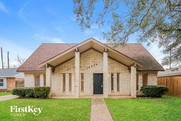 Houston house for rent - a small brick house with a green lawn and a tree
