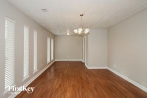 Houston house for rent - an empty living room with wood flooring and white shuttered windows