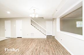 Houston house for rent - A spacious room with wooden flooring and a staircase.