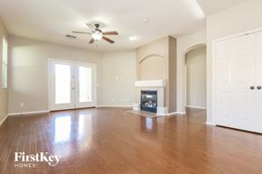 Surprise house for rent - an empty living room with a fireplace and a ceiling fan