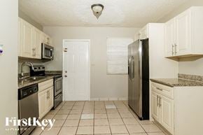 N Miami Beach house for rent - A kitchen with white cabinets and a black refrigerator.
