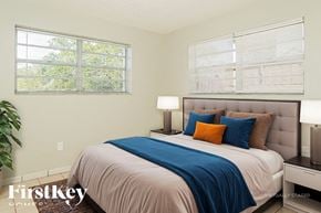 N Miami Beach house for rent - A bedroom with a bed, pillows, and a lamp.