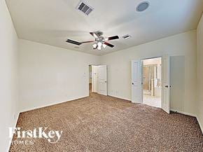 Houston house for rent - A carpeted room with a ceiling fan and a doorway leading to another room.