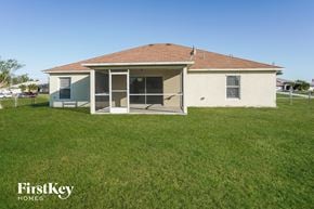 Cape Coral house for rent - a small white house with a grass yard and a fence