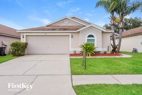 Brandon house for rent - a beige house with a driveway and a palm tree