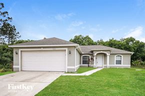 Lehigh Acres house for rent - a beige house with a garage and a green lawn