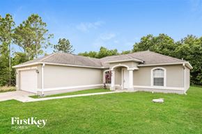 Lehigh Acres house for rent - a beige house with a green lawn and trees