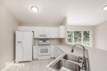 Lehigh Acres house for rent - a white kitchen with white appliances and a sink