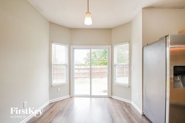 Noblesville house for rent - A kitchen with a refrigerator and a view of a backyard through the sliding glass doors.