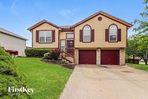 Raymore house for rent - a yellow house with a red garage door