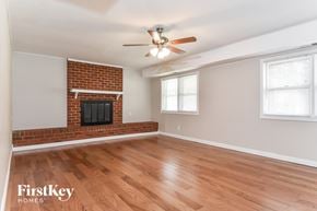 Greensboro house for rent - A room with a fireplace and a ceiling fan.