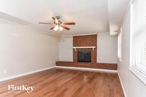 Greensboro house for rent - A room with a brick fireplace and a ceiling fan.