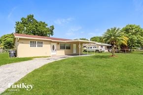 North Lauderdale house for rent - a small yellow house with a yard and a palm tree