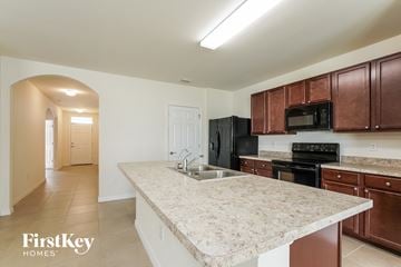 Cape Coral house for rent - A kitchen with brown cabinets and a black fridge.