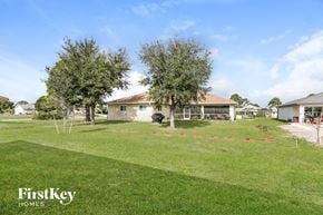 Cape Coral house for rent - A house with a lawn and trees in front of it.