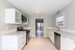 Loganville house for rent - an empty kitchen with white cabinets and stainless steel appliances