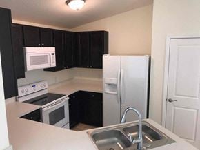 Cape Coral house for rent - a kitchen with a sink and a refrigerator