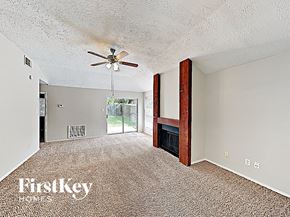 Houston house for rent - an empty living room with a ceiling fan and a fireplace