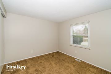 Indianapolis house for rent - the living room of a small white house with brown carpet and a window